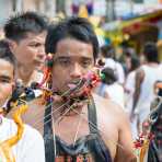 Psychic medium follower of the Bang New Shrine, witha bunch of long and thick needles pierced through his cheecks, ears, neck and tongue, taking part in a street procession during the annual Chinese vegetarian festival. Phuket, Kingdom of Thailand, Indochina, South East Asia
