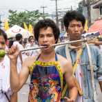 Psychic medium follower of the Bang New Shrine, with thick rod pierced through his cheeck, taking part in a street procession during the annual Chinese vegetarian festival. Phuket, Kingdom of Thailand, Indochina, South East Asia