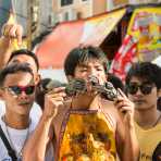 Psychic medium follower of the Bang New Shrine, with two 9mm pistols pierced through his cheecks, taking part in a street procession during the annual Chinese vegetarian festival. Phuket, Kingdom of Thailand, Indochina, South East Asia