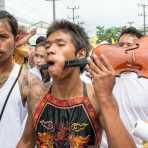 Psychic medium follower of the Bang New Shrine, with a violin neck pierced through his cheeck, taking part in a street procession during the annual Chinese vegetarian festival. Phuket, Kingdom of Thailand, Indochina, South East Asia