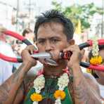 Psychic medium follower of the Bang New Shrine, with two large shears pierced through his cheecks, taking part in a street procession during the annual Chinese vegetarian festival. Phuket, Kingdom of Thailand, Indochina, South East Asia