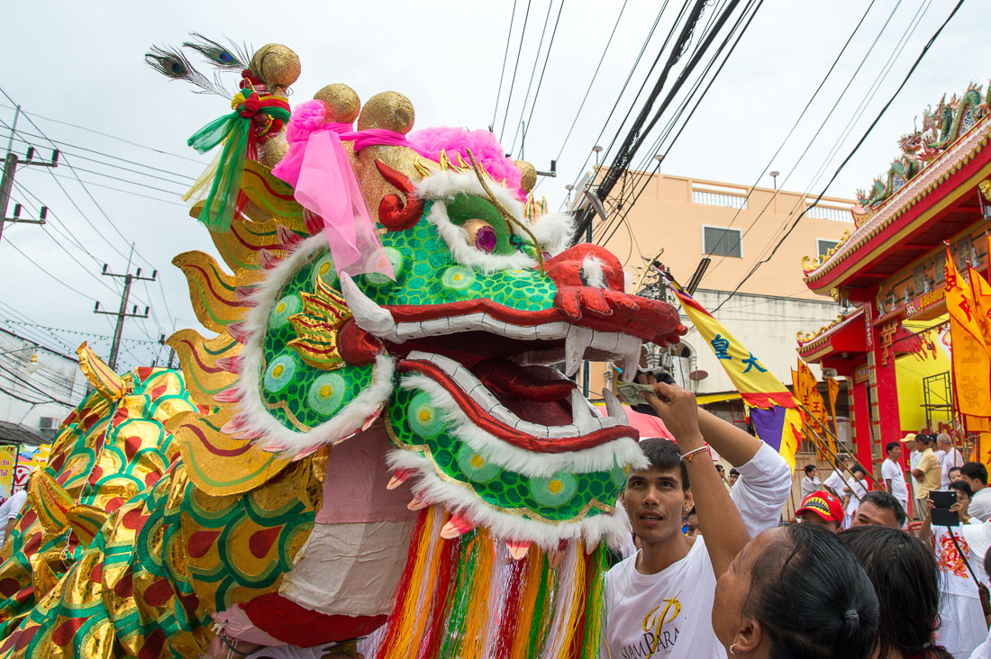 Worshippers throwing alms in the mouth of a Chinese dragon on the street of Phuket during the annual Chinese vegetarian festival. Kingdom of Thailand, Indochina, South East Asia