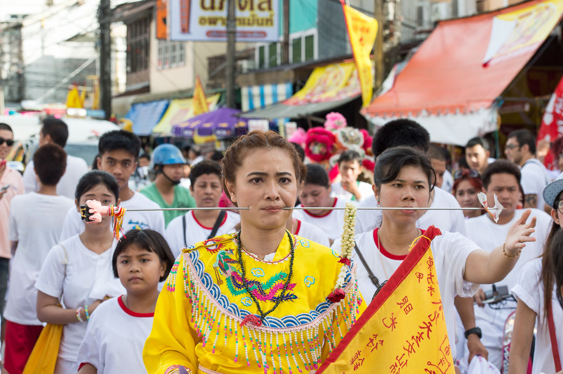 Female psychic medium follower of the Bang New Shrine with a long and thick needle pierced through her cheek, taking part in a street procession during the Chinese annual vegetarian festival. Phuket, Kingdom of Thailand, Indochina, South East Asia