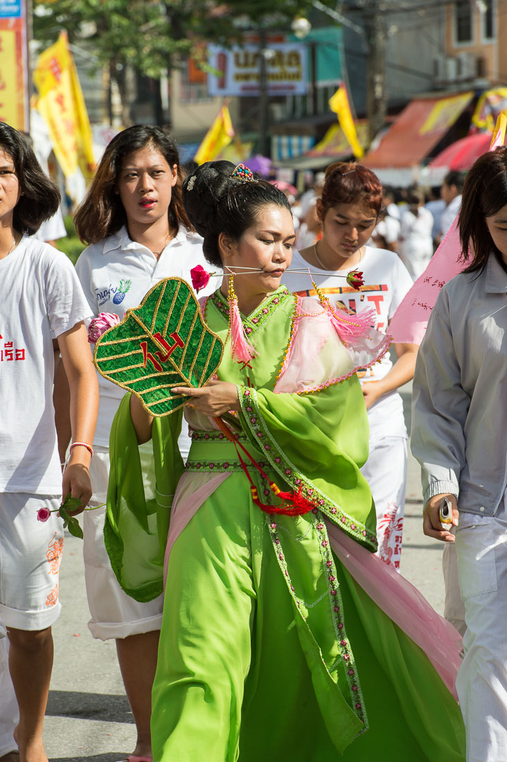 Female psychic medium follower of the Bang New Shrine with two long needles pierced through her cheeks, taking part in a street procession during the Chinese annual vegetarian festival. Phuket, Kingdom of Thailand, Indochina, South East Asia