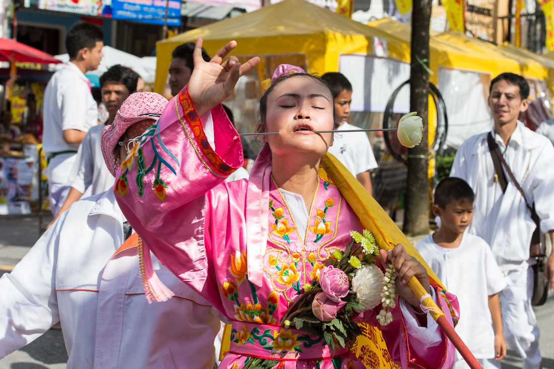 Female psychic medium follower of the Bang New Shrine with a long and thick needle pierced through her cheek, taking part in a street procession during the Chinese annual vegetarian festival. Phuket, Kingdom of Thailand, Indochina, South East Asia