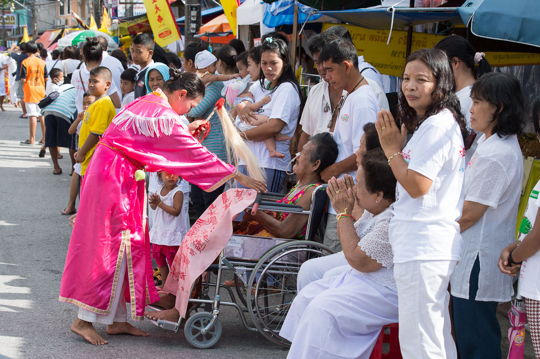 Female psychic medium follower of the Bang New Shrine, giving spiritual blessing to a sick woman in a wheel chair, during the street procession in the annual Chinese vegetarian festival. Phuket, Kingdom of Thailand, Indochina, South East Asia