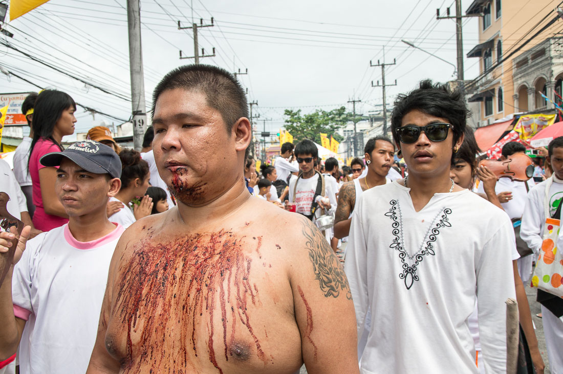 Psychic medium follower of the Bang New Shrine, his chest covered by blood from self inflicted injuries on his face, taking part in a street procession during the annual Chinese vegetarian festival. Phuket, Kingdom of Thailand, Indochina, South East Asia