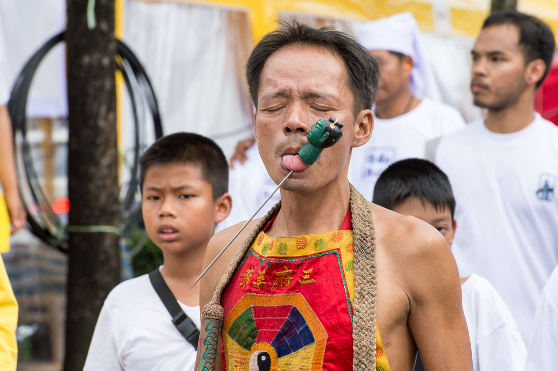 Psychic medium follower of the Bang New Shrine, with a long and thick needle pierced through his tongue, taking part in a street procession during the annual Chinese vegetarian festival. Phuket, Kingdom of Thailand, Indochina, South East Asia