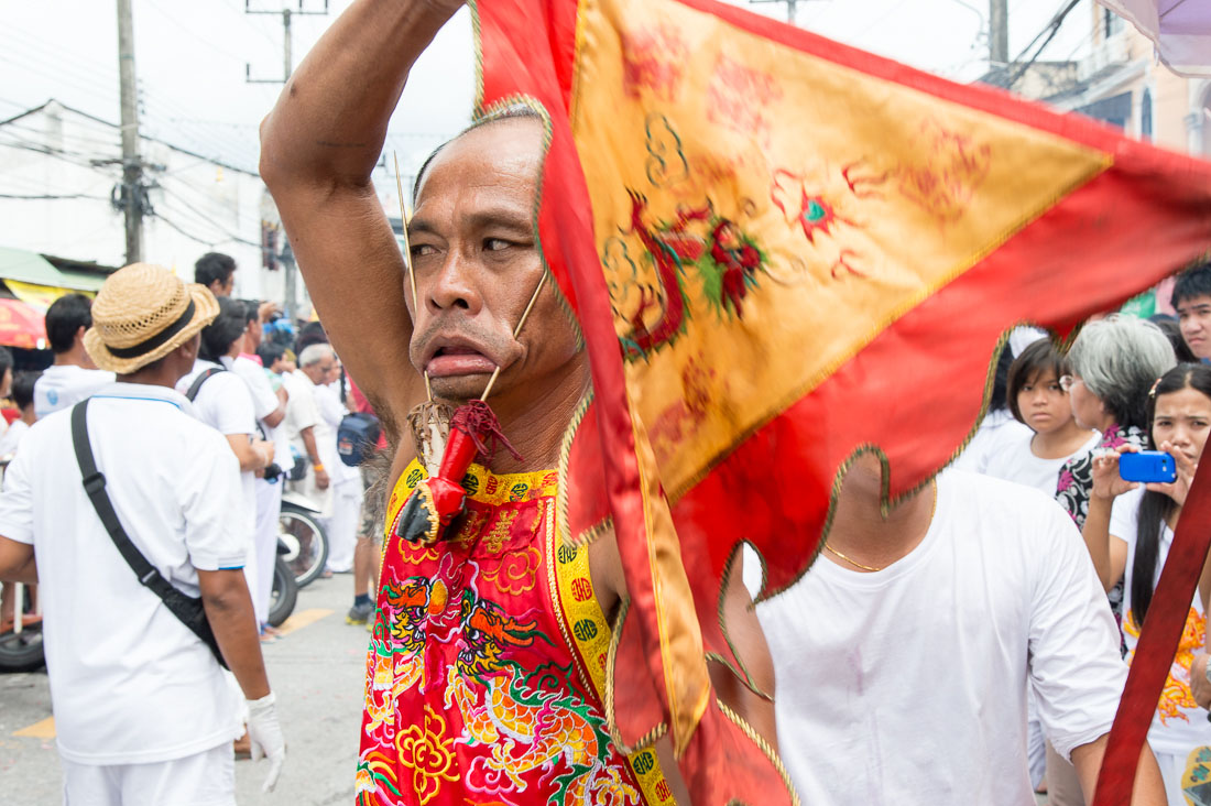 Psychic medium follower of the Bang New Shrine, with two long and thick needles pierced through his cheecks, taking part in a street procession during the annual Chinese vegetarian festival. Phuket, Kingdom of Thailand, Indochina, South East Asia