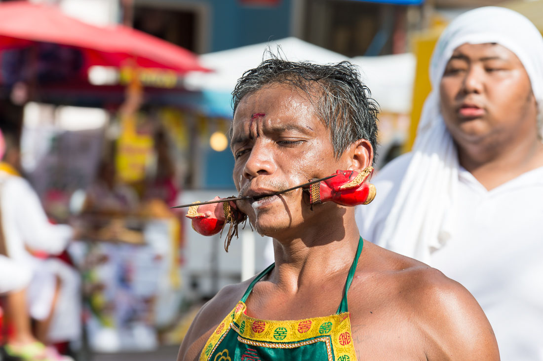 Psychic medium follower of the Bang New Shrine, with two long and thick needles pierced through his cheecks, taking part in a street procession during the annual Chinese vegetarian festival. Phuket, Kingdom of Thailand, Indochina, South East Asia