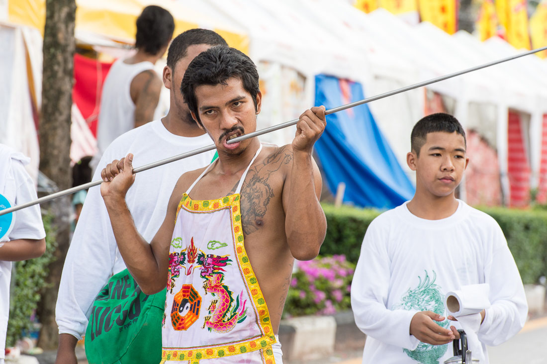 Psychic medium follower of the Bang New Shrine, with a very long and thick rod pierced through his cheeck, taking part in a street procession during the annual Chinese vegetarian festival. Phuket, Kingdom of Thailand, Indochina, South East Asia