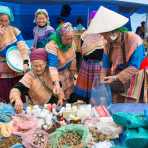 Women from the Flower Hmong people ethnic minority, buying medicines and cosmetics at the busy Bac Ha market, Lao Cai Province, Viet Nam, Indochina, South East Asia.