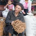 Man from the Flower Hmong people ethnic minority group, wearing his traditional beret, selling incense burning sticks at busy market in Lung Phin, Ha Giang Province, Viet Nam, Indochina, South East Asia