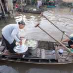 An old woman selling banh bao early morning at the Cai Rang vegetable floating market in the Mekong River Delta, Can Tho, Hau Giang Province, Viet Nam, Indochina, South East Asia.