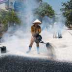 Vietnamese worker puoring hot tar on road under construction, Yen The, Yen Bai Province, Viet Nam, Indochina, South East Asia.