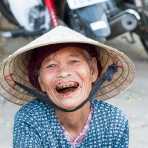 Old woman, smiling and showing her stained teeth and lips because of her addiction of chewing paan (lime, tobacco, areca nuts and betel leaves). Hoi An market, Quang Nam province, Viet Nam, Indochina, South East Asia.