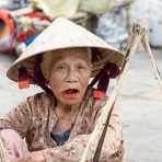 Old woman, smiling and showing her stained teeth and lips because of her addiction of chewing paan (lime, tobacco, areca nuts and betel leaves). Hoi An market, Quang Nam province, Viet Nam, Indochina, South East Asia.