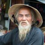 Old man at the Hoi An market very proud of his long white beard. Quang Nam Province, Viet Nam, Indochina, South East Asia.