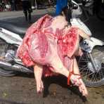 A Honda Wave motorcycle fully loaded with two large dead pigs to be delivered to a local butcher in Hanoi. Viet Nam, Indochina, South East Asia. Samsung smartphone.
